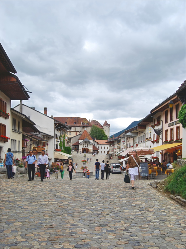 28 - The main street and cobblestone square of the medieval town of Gruyères in the Canton of Fribourg, Switzerland, looking toward the Chapelle à Calvaire